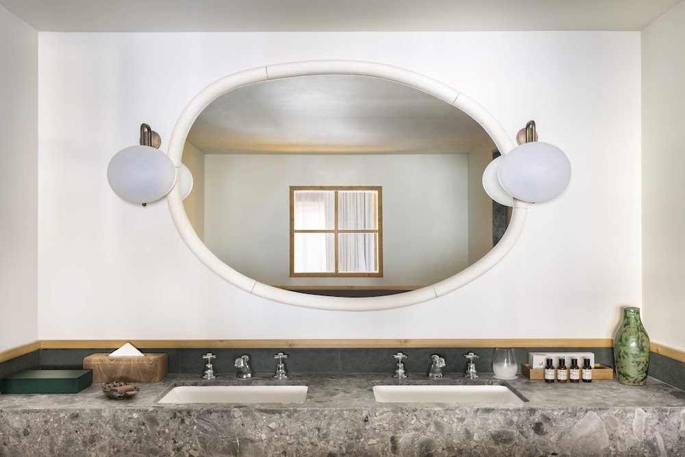 marble bathroom reflecting the chalet window in the oval mirror